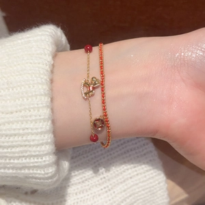Close-up of double-layer horse pendant bracelet with red cord and gold chain on wrist