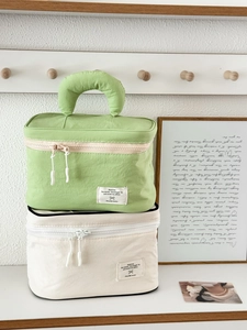 Detail of green and cream nylon makeup bags featuring sturdy handles and dual zippers
