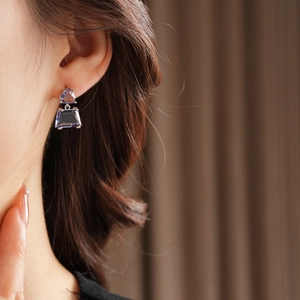 Close-up of model wearing light purple geometric silver earrings with zircon stones
