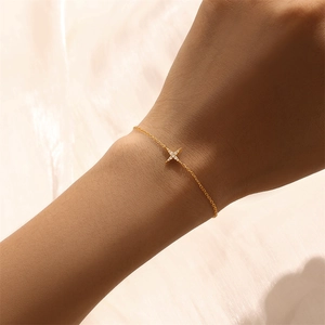Detailed close-up of a slender gold star bracelet with zircon stones on a female wrist
