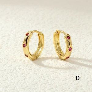 Macro view of gold hoop earrings with textured wavy design and red zircon inlay