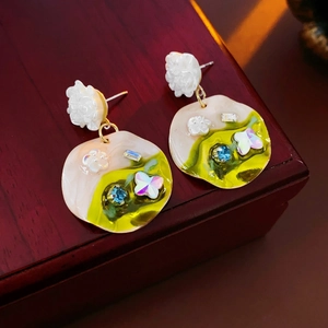 Detail of floral earrings with crystals and colorful butterflies on a wooden box