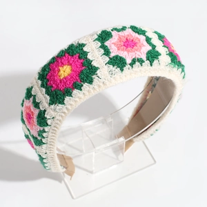 Detail of handmade crochet flower headband with colorful embroidery on white knit