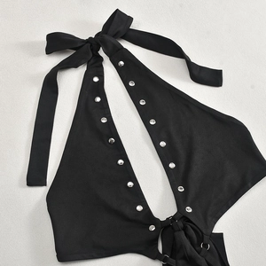 Détail du haut dos nu noir avec rivets argentés et nœud papillon élégant sur le col