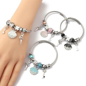 Detail view of silver stainless steel charm bracelet with shell and dancer pendants