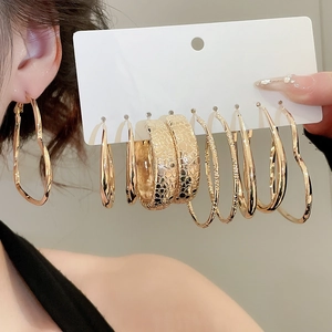 Close-up of 6 pairs golden resin hoop earring set displayed on ear and card