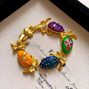 Detailed view of Fabergé style vintage bracelet with enamel eggs and golden bow accents