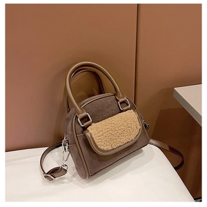 Detailed view of the brown suede handbag with beige plush fleece pocket and silver hardware
