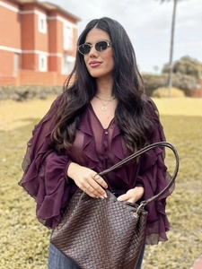 Deep purple ruffled chiffon V-neck blouse paired with a brown woven leather tote bag