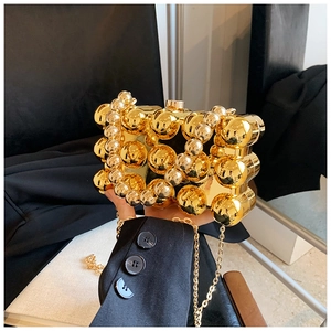 Detail view of a gold hardshell clutch bag with decorative beads and chain strap