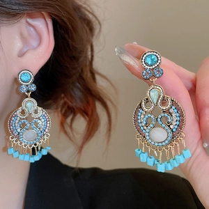 Detail of bohemian gold earrings with turquoise stones and beaded fringe tassels