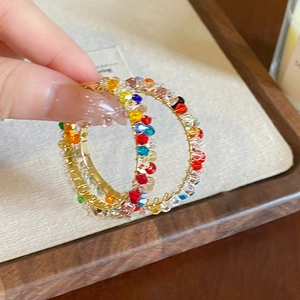 Macro shot of colorful faceted crystal beads wrapped on gold-tone hoop earrings