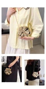 Detail of flower shaped gold metallic clutch bag with mirror finish and chain strap