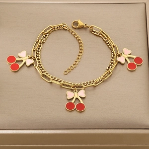 Detail view of double-layered gold bracelet with cherry pendants and lobster clasp