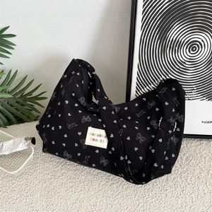 Detail of black corduroy hobo bag with heart and bow patterns and woven label