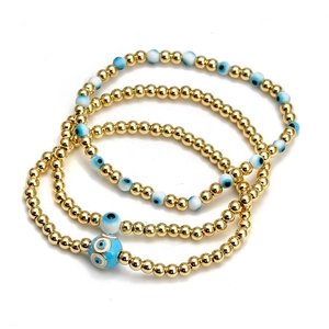 Close-up of three Evil Eye beaded bracelets featuring gold beads and blue resin charms