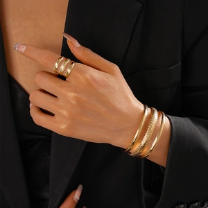 Close-up of gold plated layered bracelet and ring set on model wearing black suit