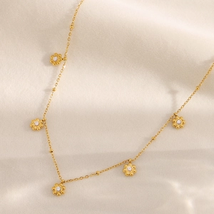 Detail einer 18K vergoldeten Edelstahlkette mit fünf Zirkonia-Blütenanhängern
