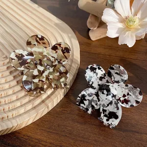 Floral acetate hair claw clips in tortoiseshell and marble patterns on wood tray