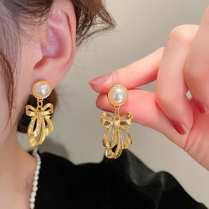 Detailed close-up of vintage gold bow earrings with pearls and crystal accents