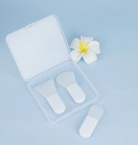 Three mini silicone face mask brushes with clear travel case on blue background