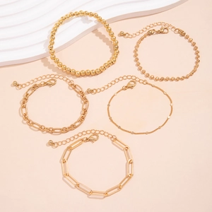 Detailed flat lay of a five-piece gold alloy bracelet set with heart charm and beads