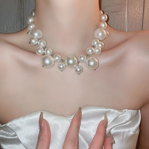 Close-up of layered irregular faux pearl necklace with silver chain on model collarbone