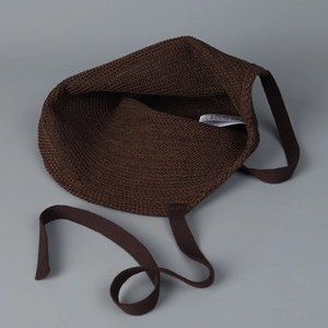 Detail showing the inner label and thick knit texture of the dark brown woven handbag