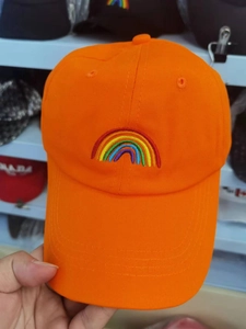 Detailed view of vibrant rainbow embroidery on orange cotton fabric of a baseball cap