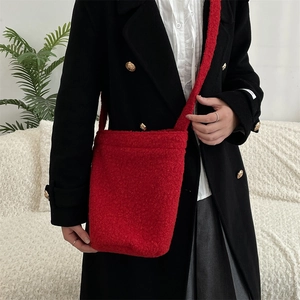 Gros plan du sac seau en peluche rouge vif en polaire teddy avec bandoulière assortie