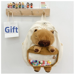 Detail of cute cream schoolbag featuring a plush capybara and colorful pom-poms