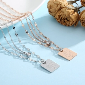 Detail of silver and rose gold layered necklaces with engraved square pendant and crystals