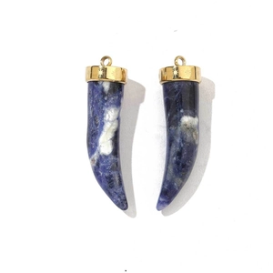 Detailed close-up of crescent horn pendants with blue lapis lazuli and engraved gold caps