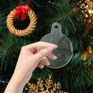 Close-up of clear acrylic Christmas ornament blanks held against a decorated tree