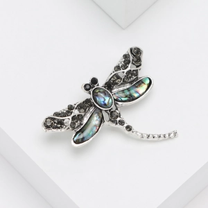 Vintage dragonfly brooch with abalone shell and black rhinestones on a white background