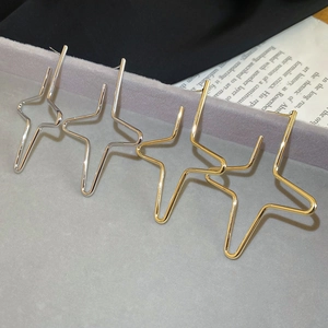 Detailed view of geometric gold and silver star earrings on a gray jewelry tray display