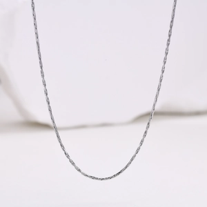 Close-up of 1mm silver stainless steel snake chain necklace on white stone surface