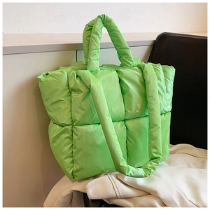 Detail of bright green quilted puffer tote bag featuring soft padded texture and top handle