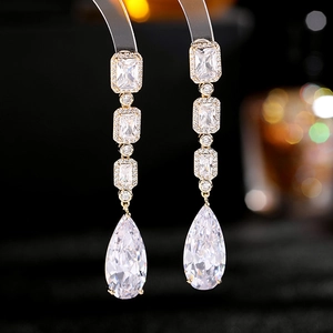Detailed macro view of long pear-shaped drop earrings with clear zircon crystals and gold base