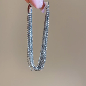Macro detail of multi-layered silver chain bracelet with intricate bead and snake link texture