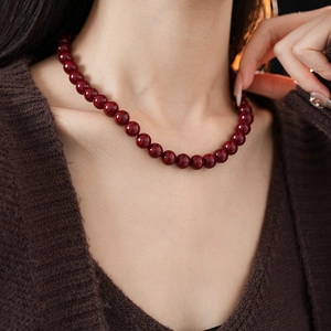 Close-up of deep red beaded titanium steel necklace worn on model for a vintage look