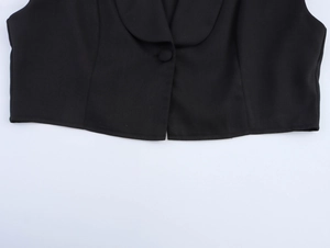 Detailed view of black tailored vest with button fastening and sleek suit fabric