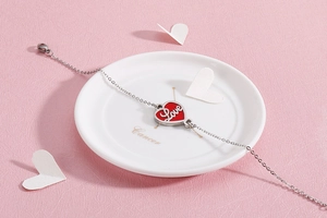 Detail of silver stainless steel bracelet with a red heart pendant and Love engraving