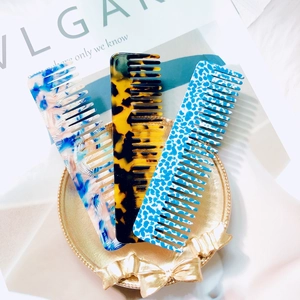 Three acetate hair combs with marble, tortoise, and leopard patterns in a gold tray