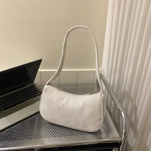Minimalist white corduroy underarm bag displayed on a sleek metal stand in a lifestyle setup