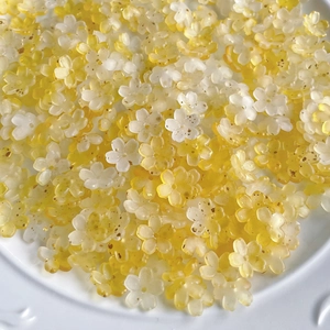 Close-up of yellow and white gradient resin flower beads on a white tray for jewelry making