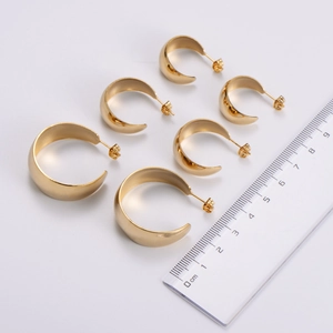 Three pairs of gold C-shaped hoop earrings in different sizes with a ruler for scale