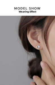 Detail of Saturn-inspired silver hoop earring with blue glaze stone on a model ear
