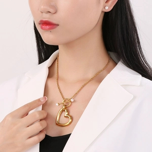 Modèle portant un collier cœur doré avec fermoir en T, perles et boucles d'oreilles