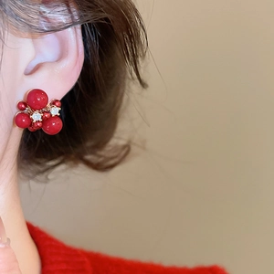 Detailed view of red zircon cluster stud earrings worn by a model in red knitwear